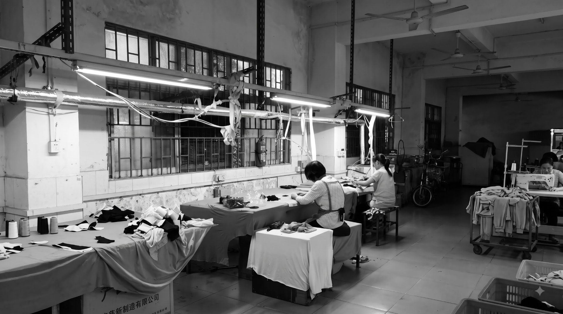 Artisans working at sewing machines in a sunlit textile workshop