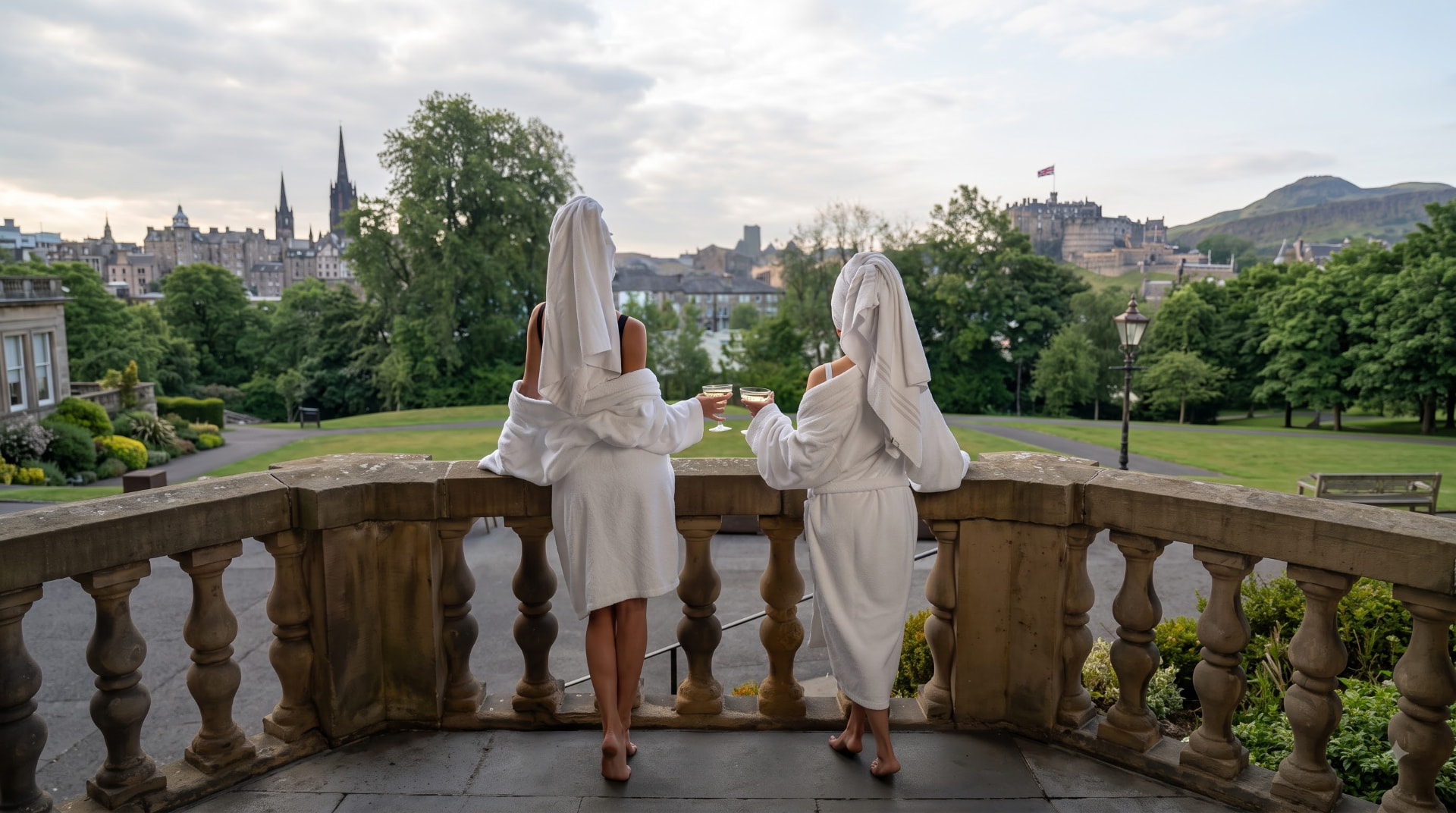 Two guests in Maison Bain bathrobes enjoying the view from a hotel terrace at sunrise